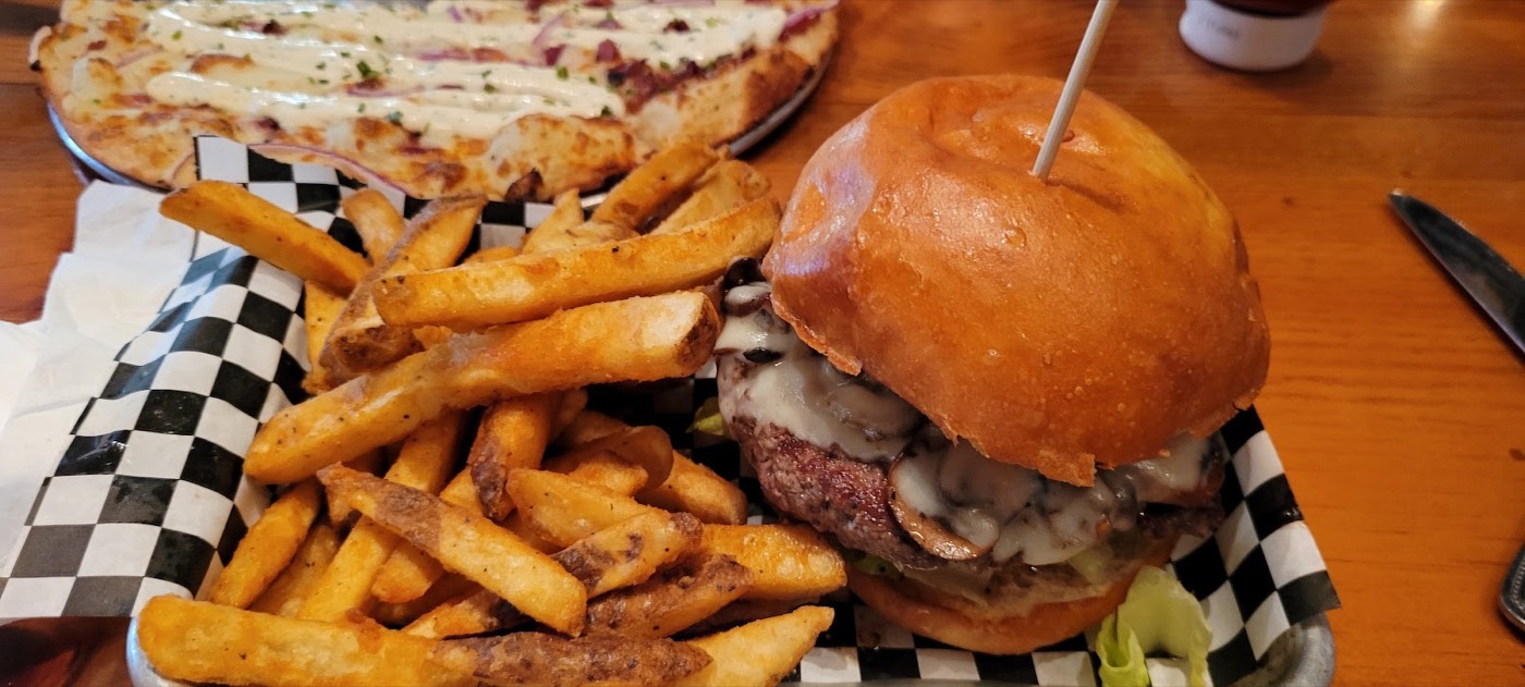 A cheeseburger on a toasted brioche bun beside a basket of fries.