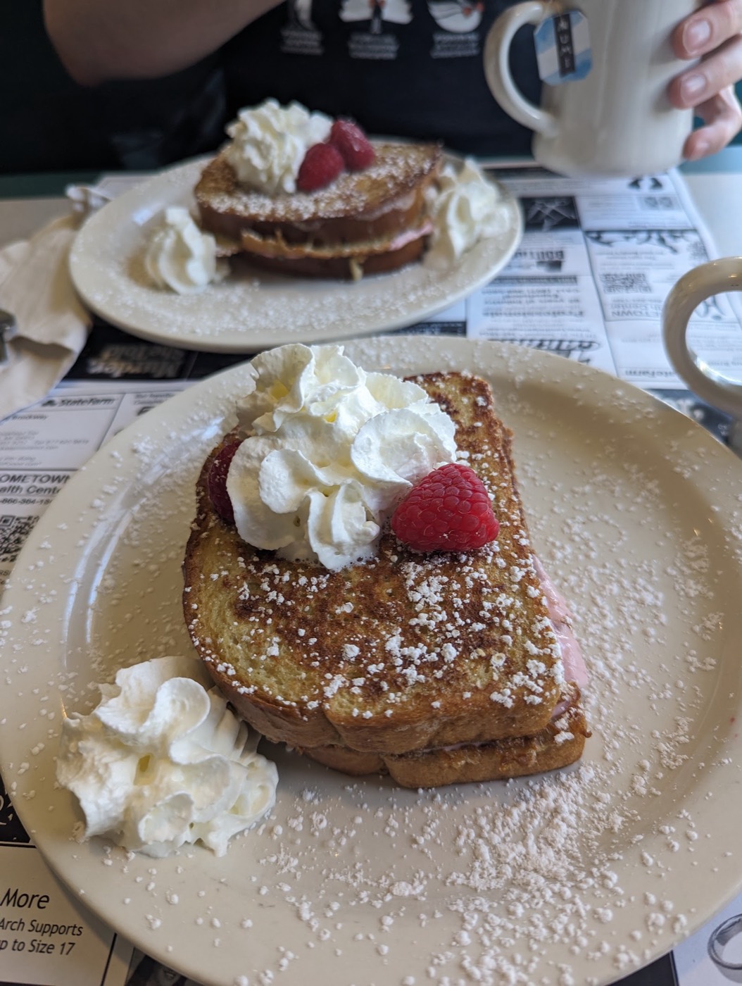 Stuffed French toast dusted with powdered sugar, topped with whipped cream and raspberries.