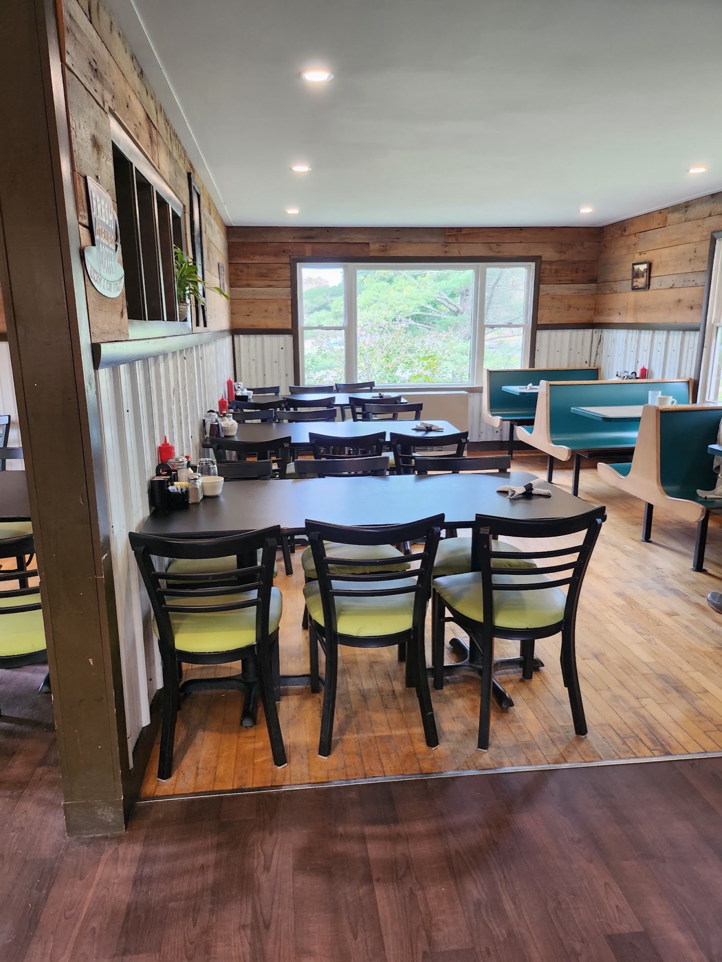 Newport Diner's dining room with wood-paneled walls, green chairs and teal booths by the windows.
